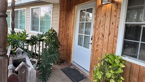A wooden exterior with a white door, a small porch area, and a birdhouse.