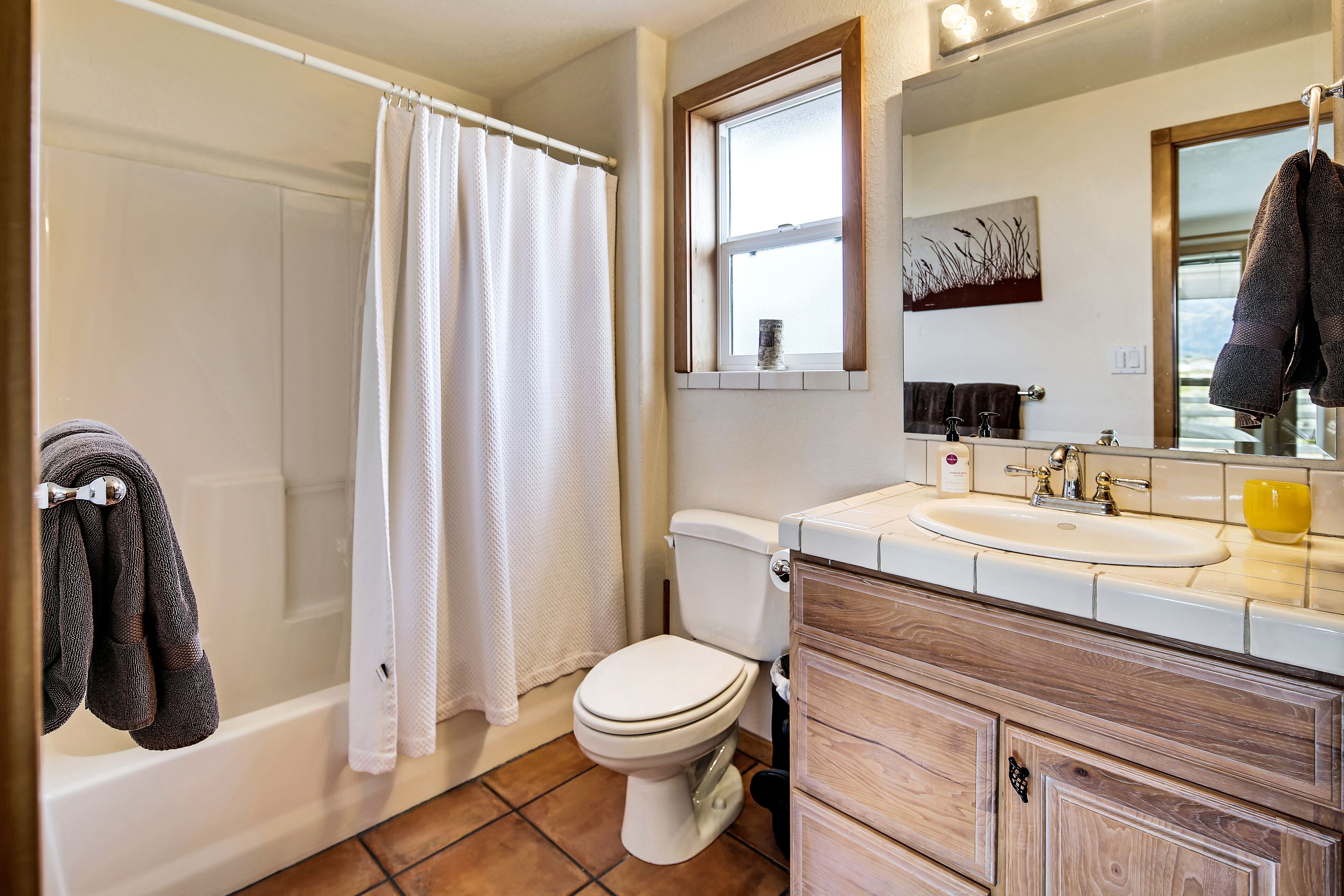 Un baño con bañera, inodoro, lavabo y tocador de madera.