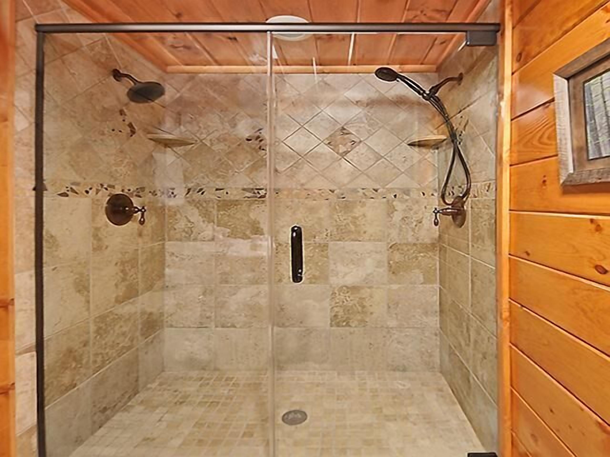 Eine gläserne Dusche mit gefliestem Boden und Holzwänden.