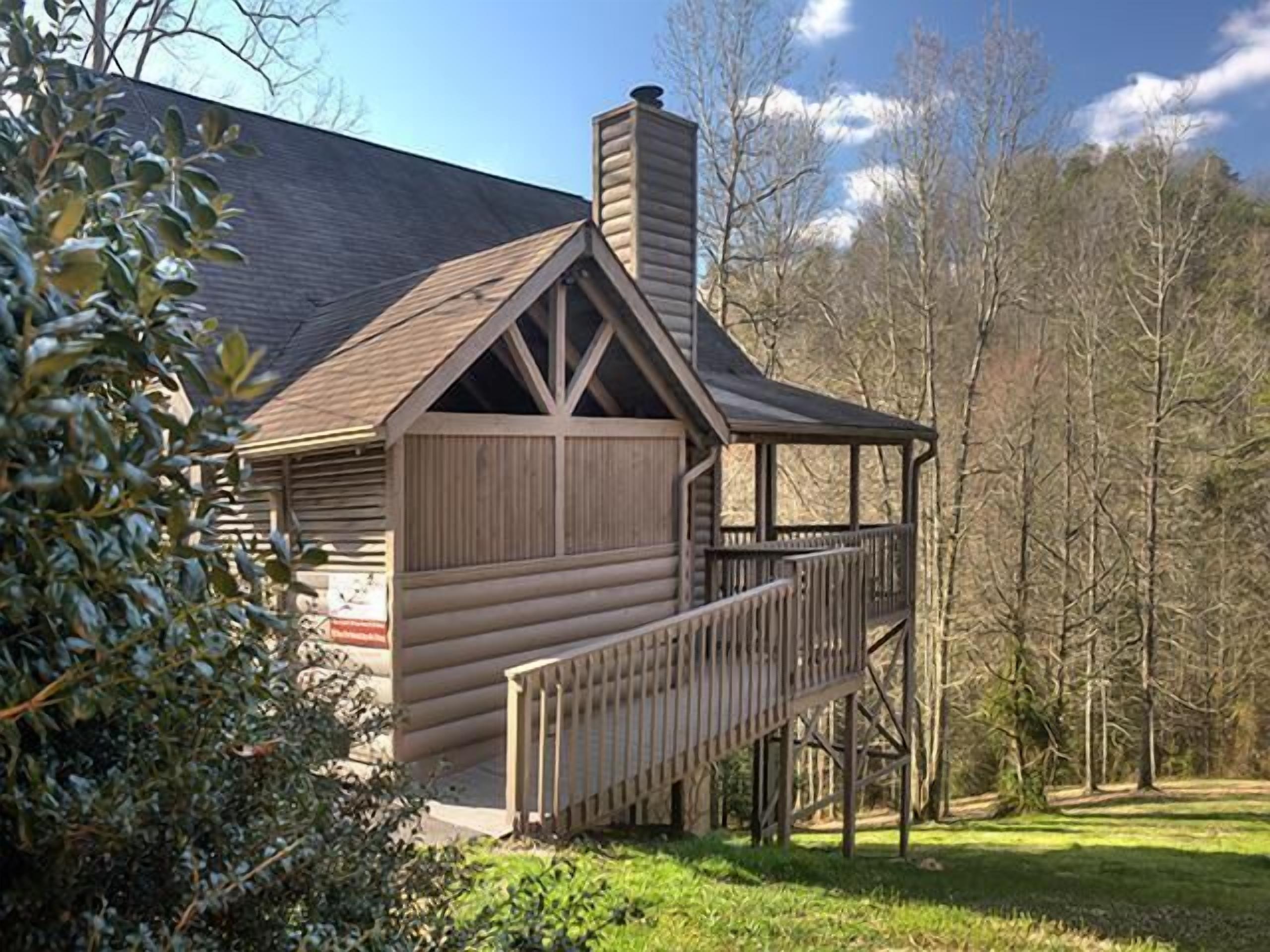 A log cabin with a wooden deck and a chimney.