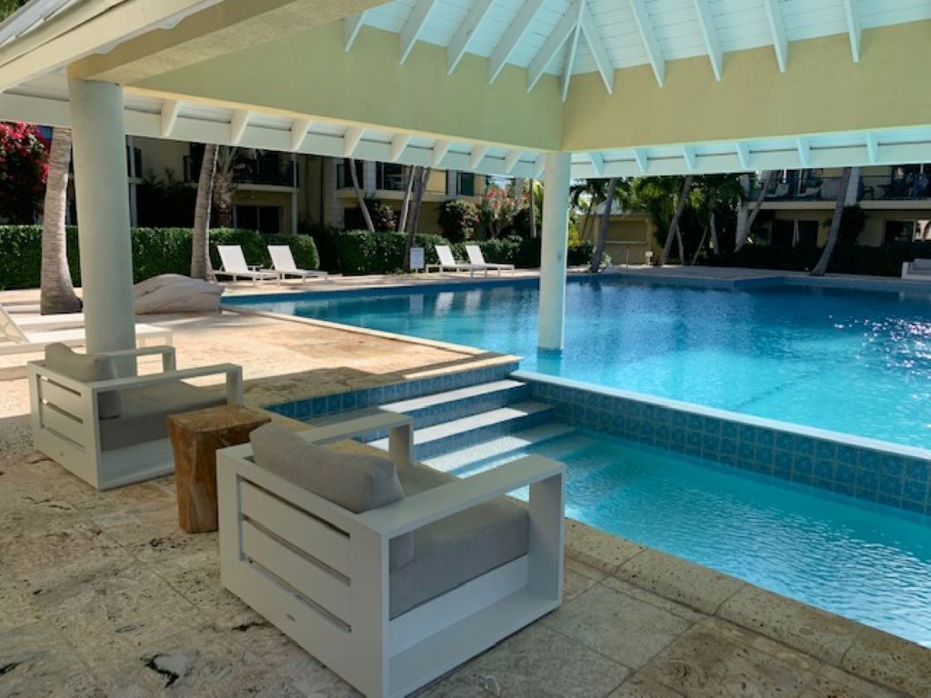 A pool area with lounge chairs and a covered seating area.