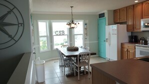 A kitchen with a dining table, chairs, a refrigerator, and a stove. - Gulf View 4/4.5-Seacliffs /dog friendly/community pool/ steps to beach-SPECIALS! (Port St Joe)