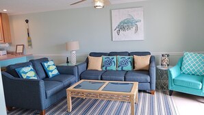 A living room with a sofa set, a coffee table, and a teal armchair. - Gulf View 4/4.5-Seacliffs /dog friendly/community pool/ steps to beach-SPECIALS! (Port St Joe)
