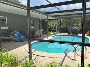 A covered outdoor swimming pool with a patio area, including a table and chairs, and a bicycle. - Waterfront freshwater paradise with pool! Swim with manatees in our backyard! (Crystal River)