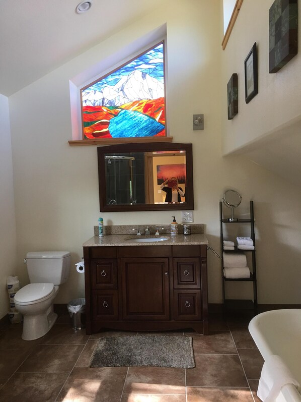 Un baño con inodoro, lavabo, tocador y un espejo grande.