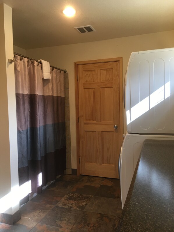 A bathroom with a shower curtain, a wooden door, and a washing machine.