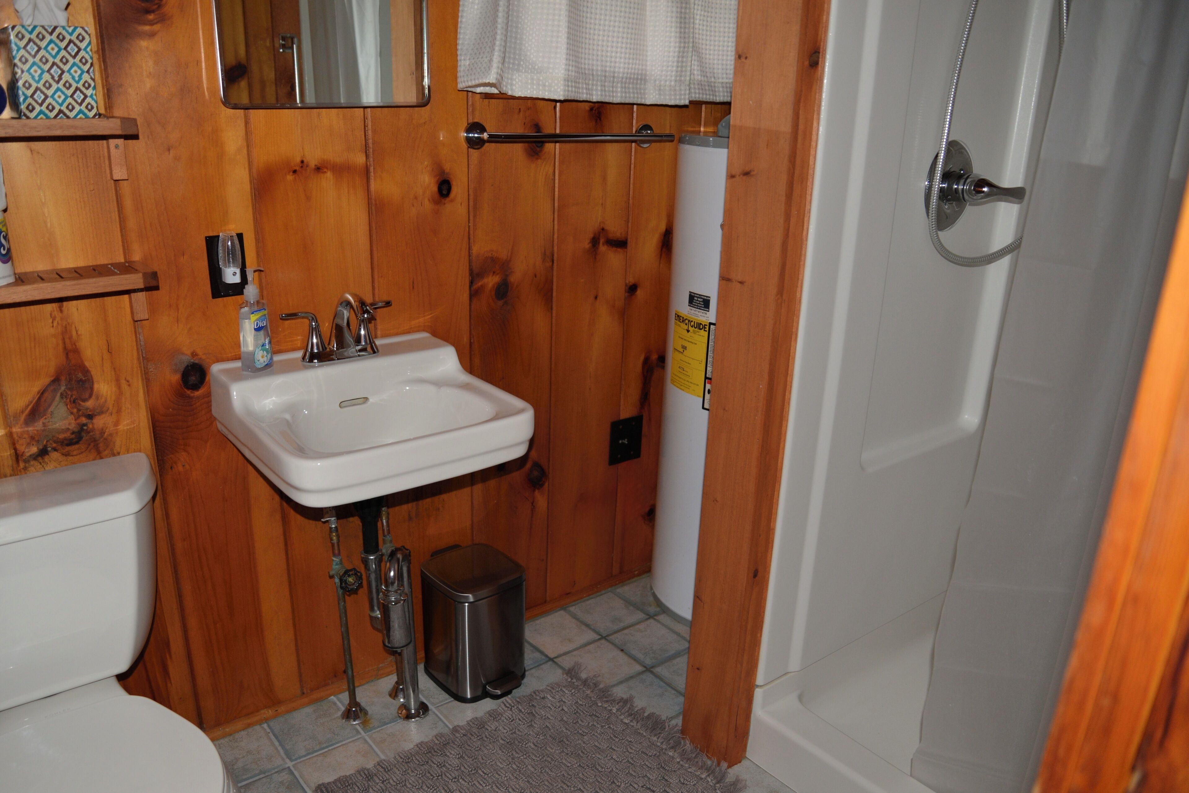 Un baño con tocador de madera, lavamanos blanco y un inodoro.