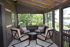 Relax in this serene outdoor seating area with a stunning lake view, featuring a round table and four comfortable chairs.