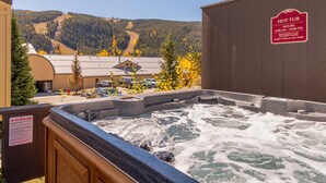 Un bain à remous avec vue sur une montagne et un bâtiment en arrière-plan.