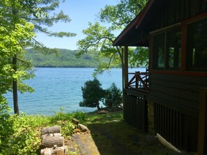 A cabin with a deck overlooking a lake, surrounded by trees. - 4 Br Lake George Waterfront Log Home W/ Dock, Rocking Porch, & Spectacular View (Silver Bay)