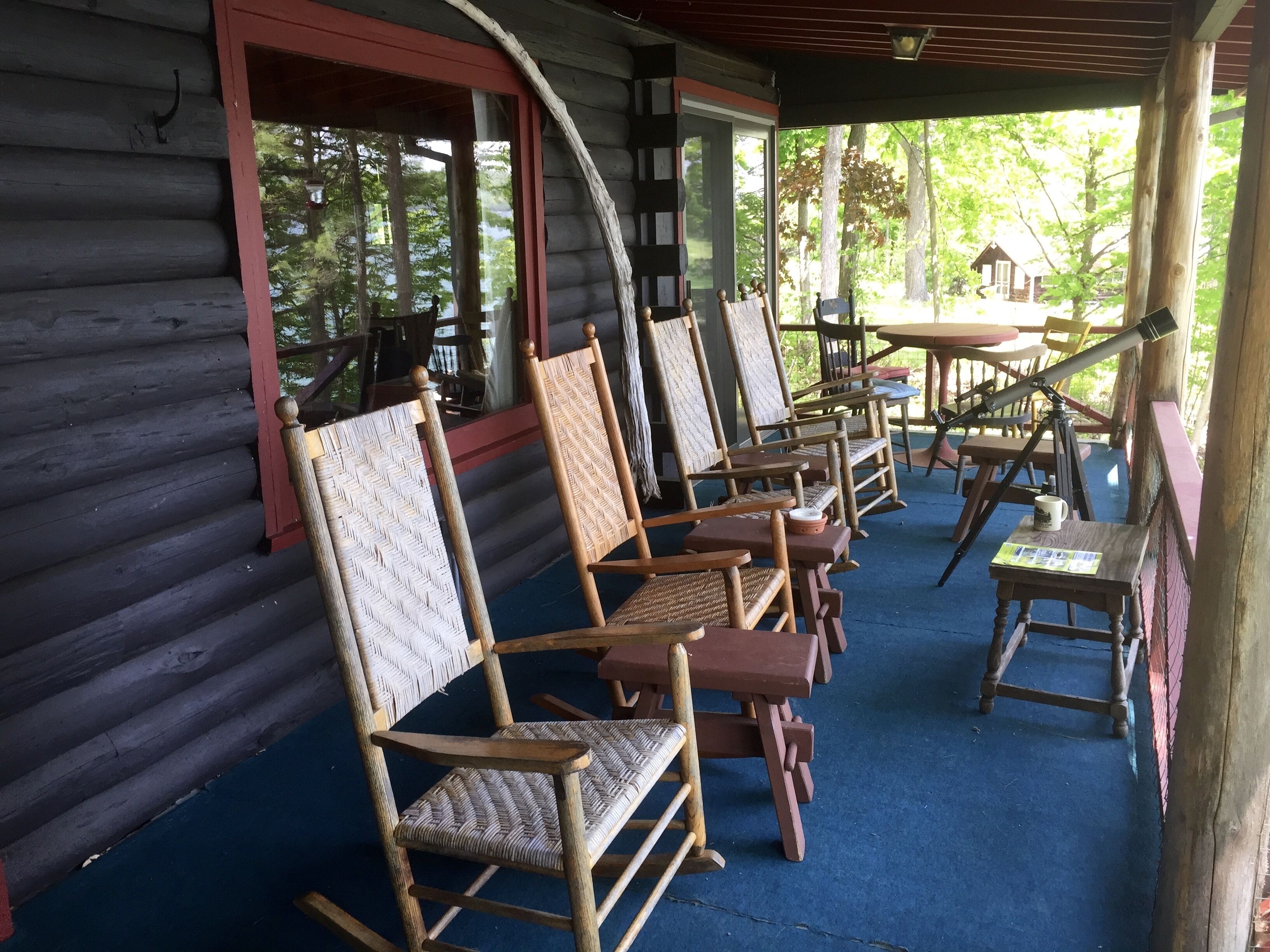 Une véranda avec des fauteuils à bascule en bois et un télescope.