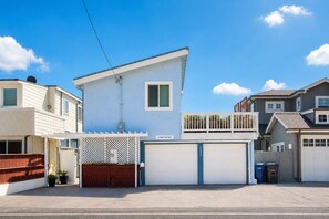 A two-story residential building with a garage, a balcony, and a fenced front yard. - Santa Cruz N At The Beach! Oceanfront w/ Amazing Sunsets! (Santa Cruz)