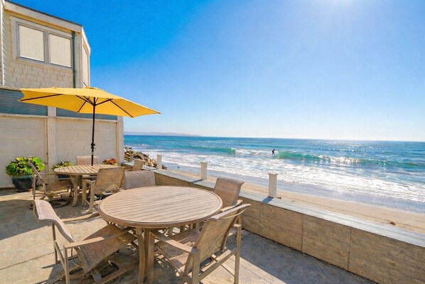 A patio with a table and chairs, a yellow umbrella, and a view of the ocean. - Santa Cruz N At The Beach! Oceanfront w/ Amazing Sunsets! (Santa Cruz)