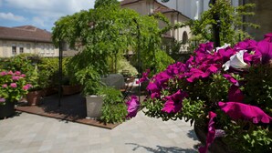 A courtyard with potted plants and flowers, a building with a tiled roof, and a paved walkway. - Casa Matilde: the coziest nest in downtown Torino (Torino)
