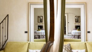 A yellow sofa with a mirror reflecting a dining area with a table and chairs. - Casa Matilde: the coziest nest in downtown Torino (Torino)