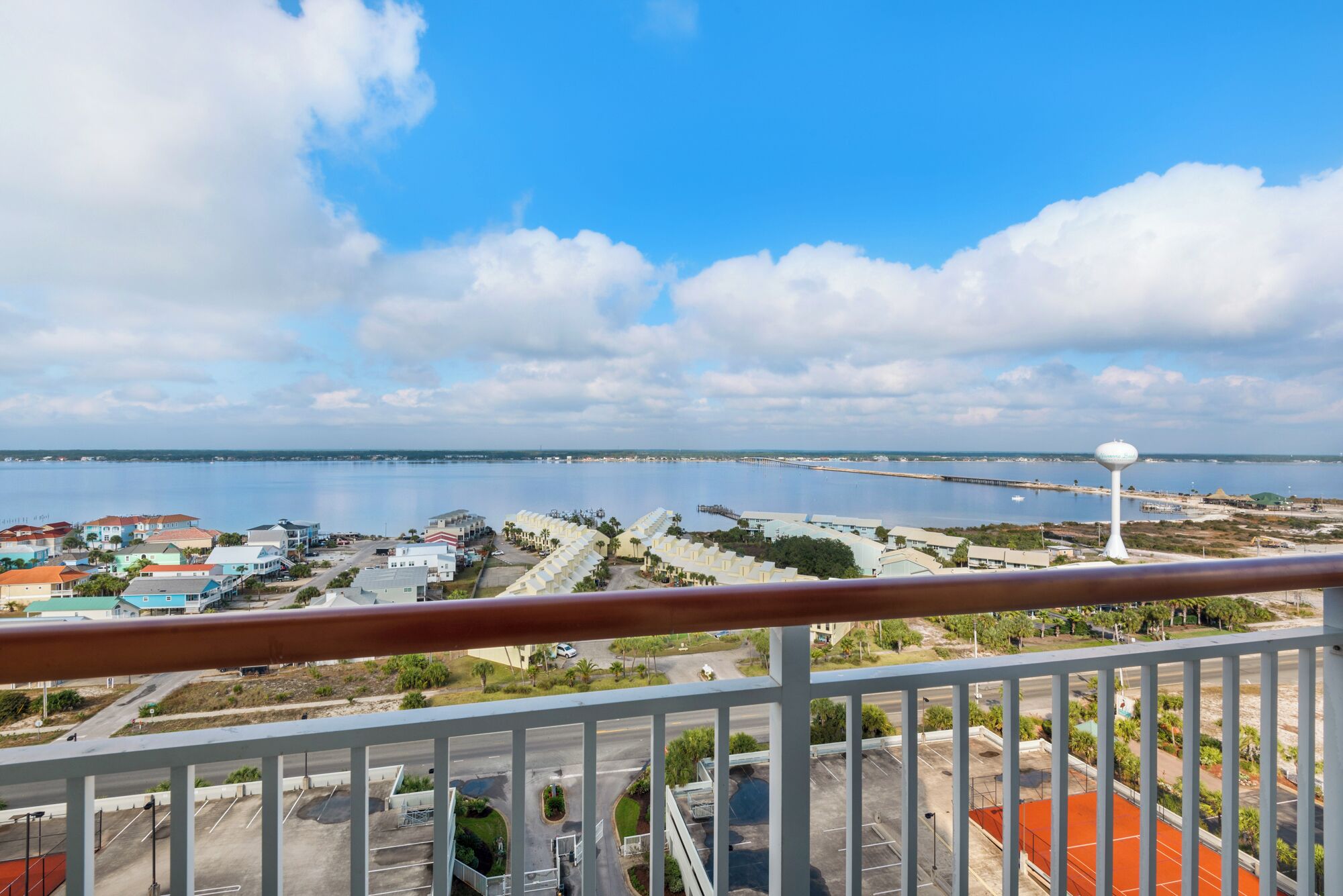A coastal view from a balcony with a clear sky, a water tower, and a marina.