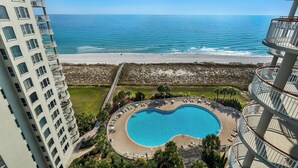 Ett hotell med pool, utsikt över stranden och höga byggnader i närheten.