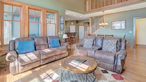 A spacious living room with two leather sofas, a coffee table, and a staircase leading to an upper level. - Townhome R21A-Mtn Home, Mtn View, Private Hot Tub, Indoor/Outdoor Pool & Hot Tub (Banner Elk)