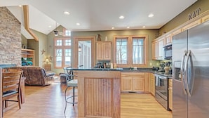 A spacious kitchen with wooden cabinets, a large island, and a stainless steel refrigerator. - Townhome R21A-Mtn Home, Mtn View, Private Hot Tub, Indoor/Outdoor Pool & Hot Tub (Banner Elk)