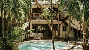 Una piscina rodeada de plantas tropicales y un edificio con balcón de madera.
