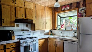 Eine Küche mit Holzausstattung, einem Herd, einer Mikrowelle und einem Kühlschrank.