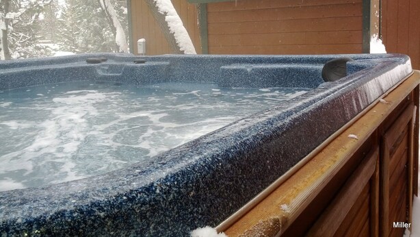 Ein Whirlpool mit Holzboden und Schnee.
