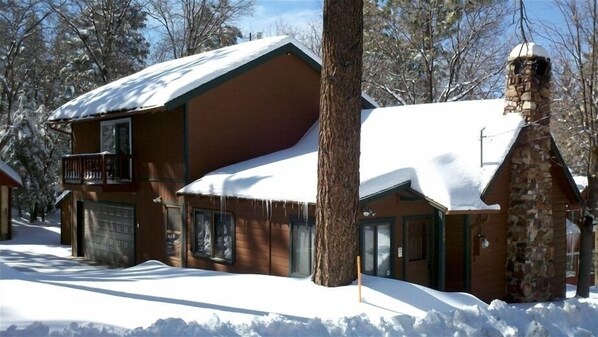 A two-story log cabin with a balcony, surrounded by snow-covered trees. - Rustic Cabin/Quiet Area/Next to Forest/Feet From Hiking Trails/Hot Tub/Garage (Big Bear Lake)
