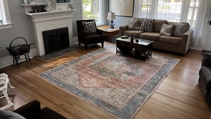 A living room with a fireplace, a sofa, a coffee table, and a patterned rug.
