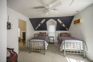 Un dormitorio con dos camas, un ventilador de techo, una ventana y un cartel en la pared.