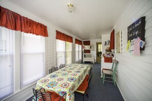 Una habitación acogedora con una mesa larga, sillas, una cama litera y una pizarra con escritura.
