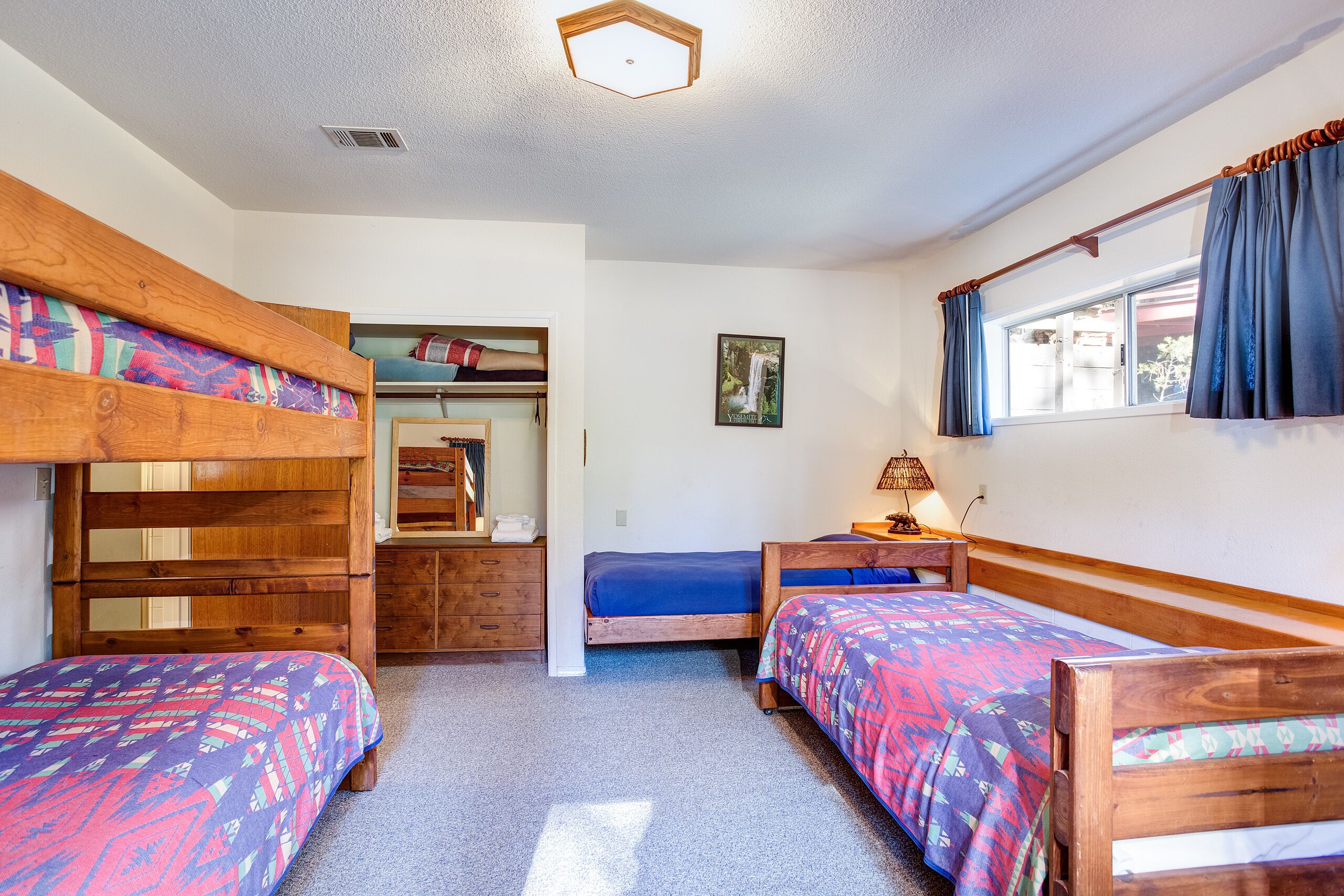 A room with bunk beds, a desk, a chair, a lamp, and a window with curtains.