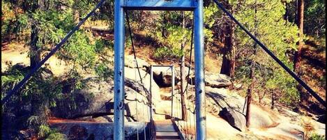 A metal bridge structure in a forested area with a wooden walkway.