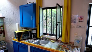 Eine Küche mit einem blauen Schrank, einer Mikrowelle, einer Kaffeemaschine und einem Spülbecken.