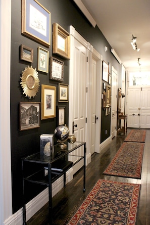 Classic hallway with framed artworks, a console table, and patterned rugs.