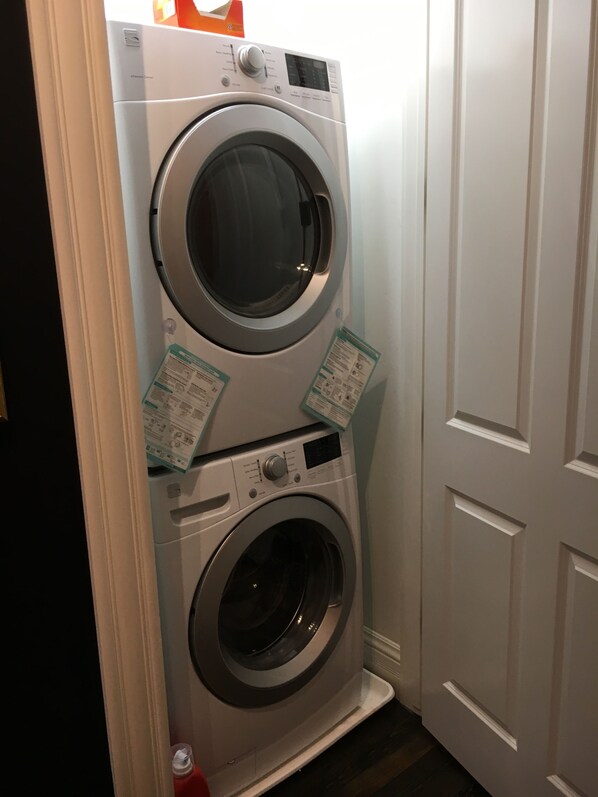 A stacked washer and dryer unit in a laundry room with a door nearby.