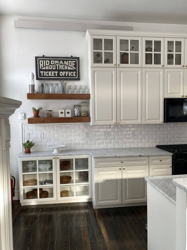 Cocina con armarios blancos, salpicadero de azulejos y suelo de madera.