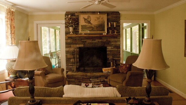 A living room with a stone fireplace, two lamps, a sofa, and a coffee table. - Relaxing Mountain Get Away (Saluda)