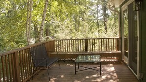 A wooden deck with a glass table and two chairs, surrounded by trees. - Relaxing Mountain Get Away (Saluda)