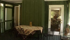 A covered porch with a table and chairs, a door leading to an interior space, and a glass railing. - Relaxing Mountain Get Away (Saluda)