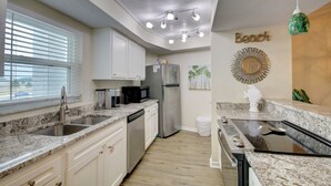 A modern kitchen with granite countertops, stainless steel appliances, and a backsplash.