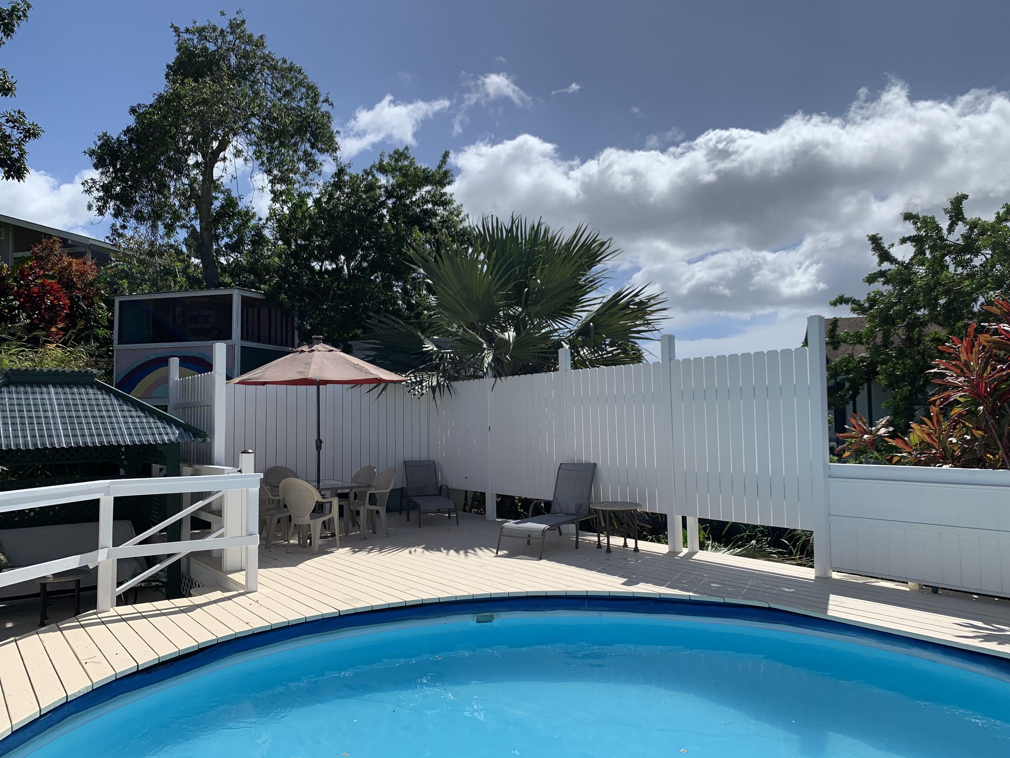 Um quintal com piscina, cerca branca e mobiliário para área externa.