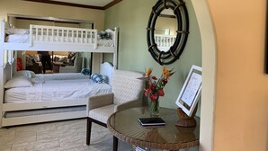 Une pièce avec un lit superposé, une table ronde en verre sur laquelle se trouve un livre, un vase de fleurs et un menu encadré accroché au mur.