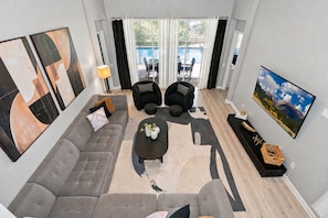 A modern living room with a grey sofa, black armchairs, a coffee table, and artwork on the walls.