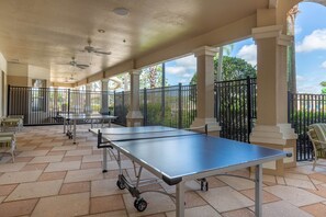 An outdoor covered area with a ping pong table, chairs, and a patio with a view of the surrounding landscape. - Paradise Villa, No rear neighbors, Minutes from Disney (Kissimmee)