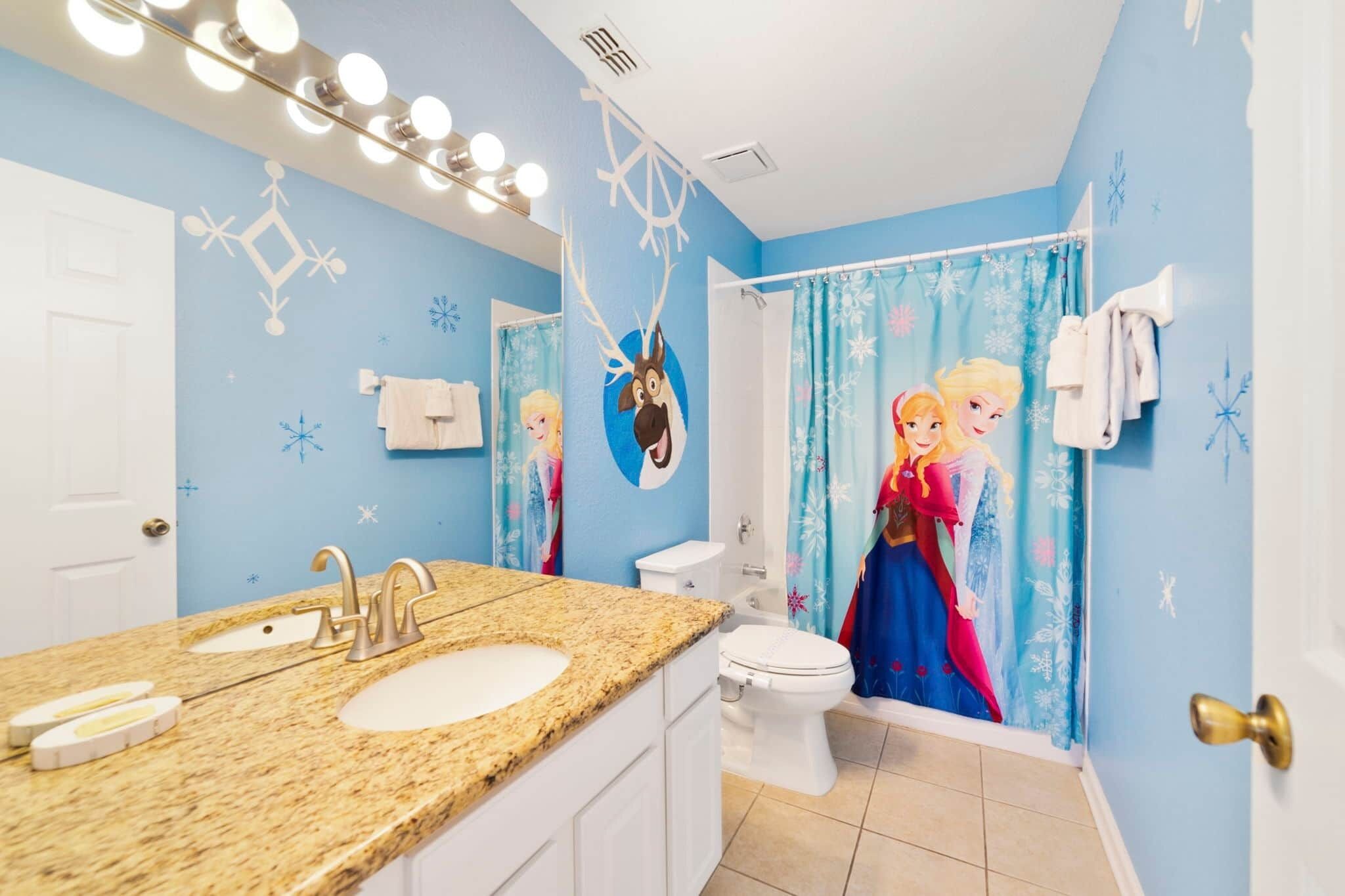 A bathroom with a sink, toilet, and shower curtain featuring animated characters.