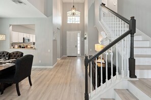 A spacious interior with a dining area, a staircase, and a kitchen.