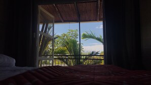 A room with a bed, a window with a view of palm trees and a clear sky. - Ballena Dorada Hotel Boutique (Bahía Ballena)