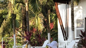 A woman sitting by a pool with white chairs and palm trees in the background. - Ballena Dorada Hotel Boutique (Bahía Ballena)