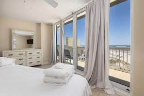 Habitación de hotel con cama, cómoda, espejo y balcón con vista a la playa.