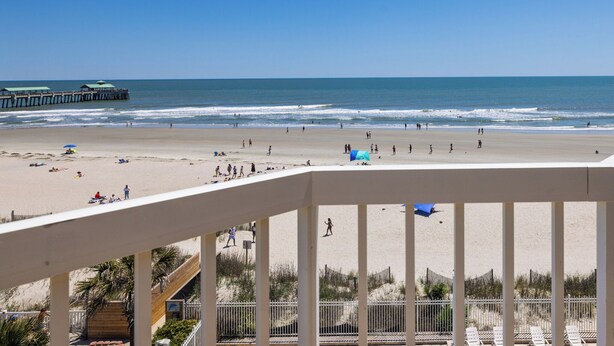 A beach view from a balcony with a pier in the background. - Stay @ The Good Life on Folly Beach (Folly Beach)